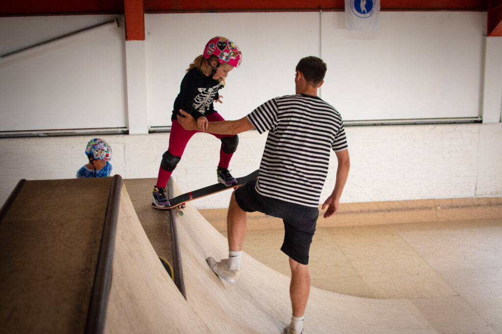 Skate with Jack, Skateboard instructor, teaches a child to skateboard